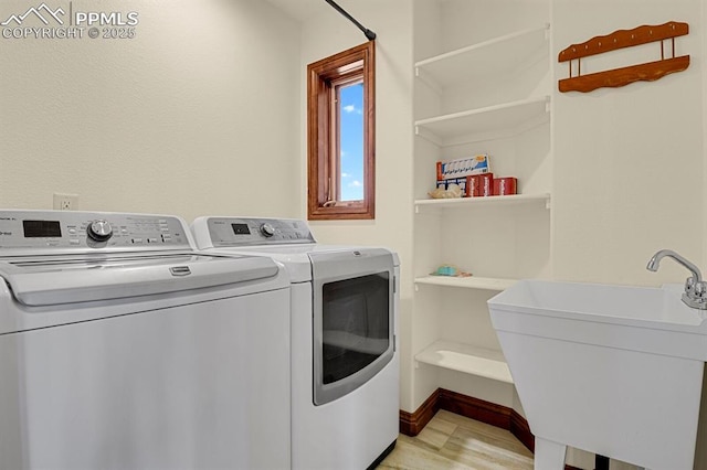 14060 Black Forest Rd, Colorado Springs, CO 80908 - clothes washing area featuring light wood-style flooring, a sink, washer and clothes dryer, baseboards, and laundry area