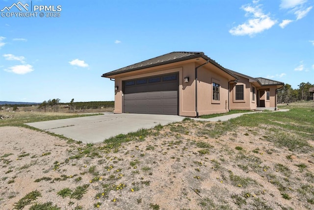 14060 Black Forest Rd, Colorado Springs, CO 80908 - view of property exterior featuring an attached garage, driveway, metal roof, and stucco siding