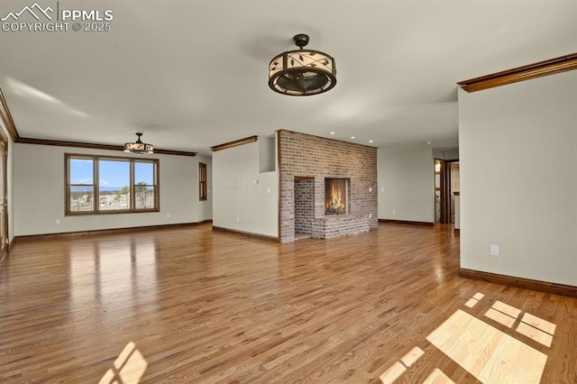 14060 Black Forest Rd, Colorado Springs, CO 80908 - unfurnished living room featuring light wood-type flooring, baseboards, recessed lighting, a brick fireplace, and ornamental molding