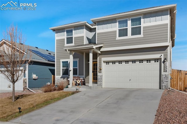 view of front of house with fence, driveway, stone siding, a garage, and board and batten siding