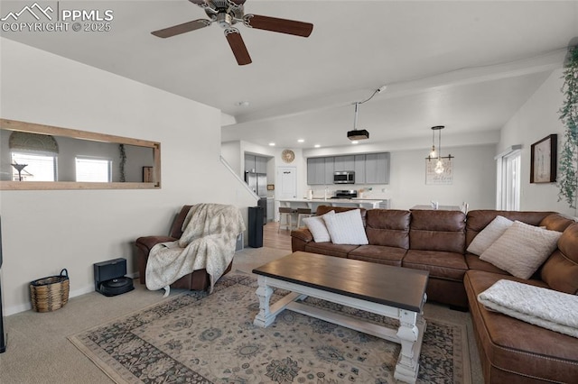 living area featuring a ceiling fan, light colored carpet, and baseboards