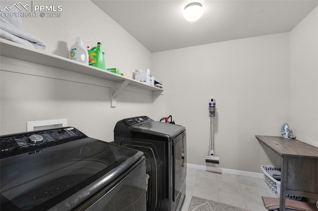 laundry room with light tile patterned floors, laundry area, washer and dryer, and baseboards