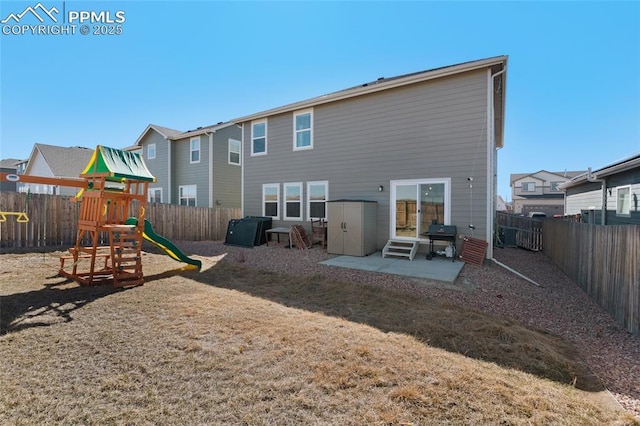 back of property with a playground, entry steps, a lawn, a fenced backyard, and a patio area