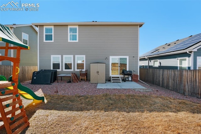 rear view of house with entry steps, a patio, a fenced backyard, a playground, and a yard