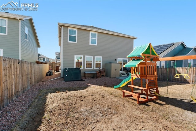 back of property with a fenced backyard and a playground