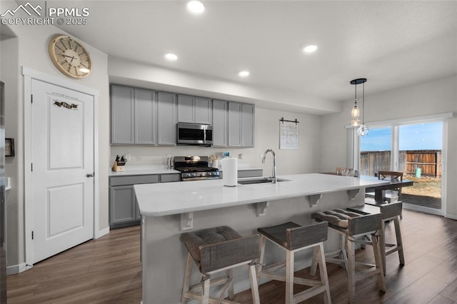 kitchen with dark wood-style floors, gray cabinets, stainless steel appliances, and a sink