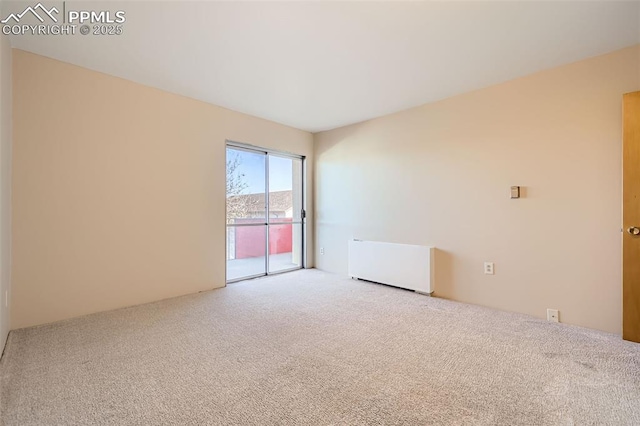 spare room featuring carpet flooring and radiator heating unit