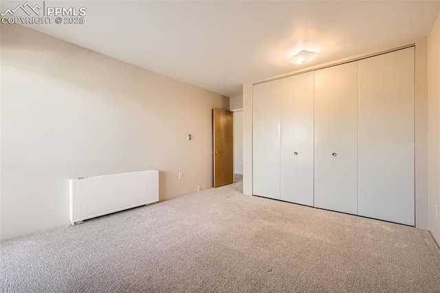 unfurnished bedroom featuring carpet flooring, a closet, and radiator heating unit