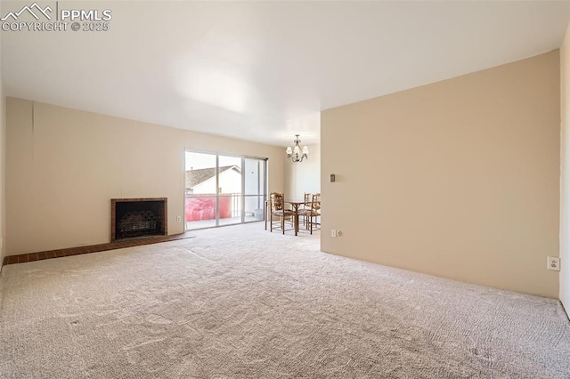 unfurnished living room featuring a fireplace with flush hearth, carpet floors, and a chandelier