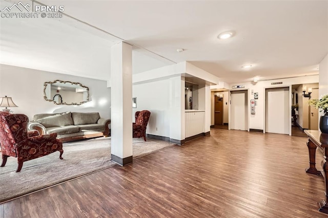 living area featuring elevator, wood finished floors, and baseboards