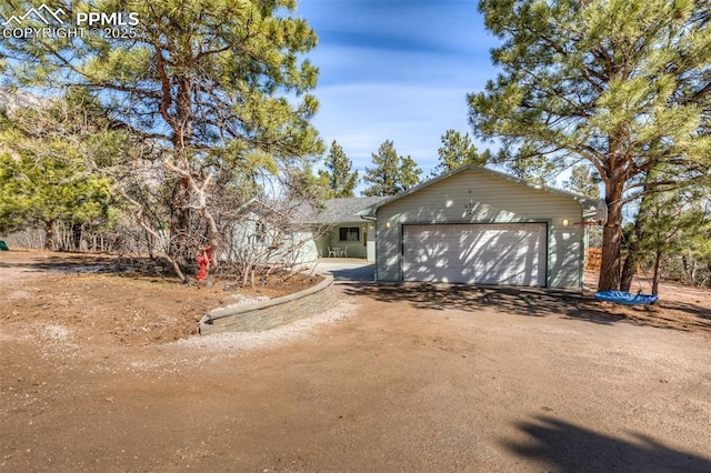 single story home with an attached garage and dirt driveway