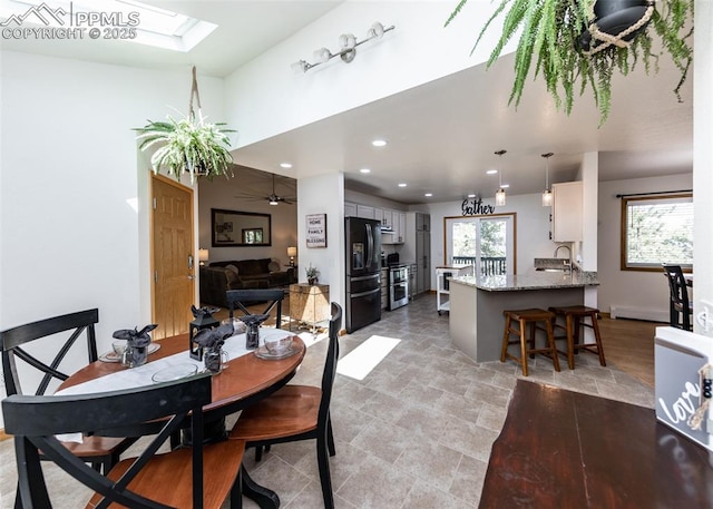 dining room with recessed lighting, a skylight, a ceiling fan, and a baseboard radiator