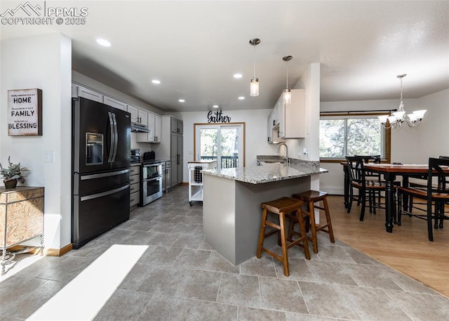 kitchen featuring light stone counters, double oven range, black fridge with ice dispenser, and a healthy amount of sunlight