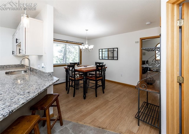 dining space featuring a notable chandelier, baseboards, and light wood finished floors