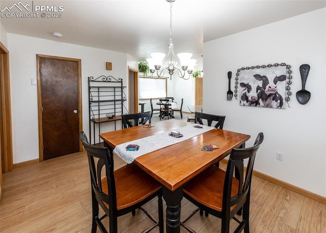 dining room with a notable chandelier, light wood-type flooring, and baseboards