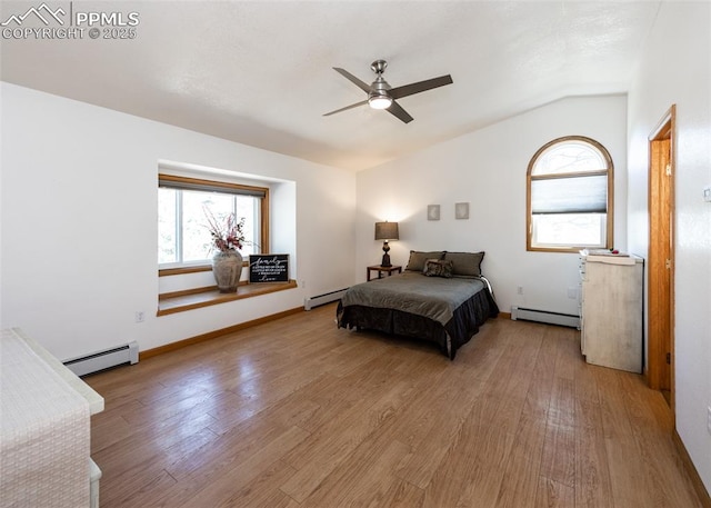 bedroom featuring light wood finished floors, baseboard heating, and vaulted ceiling