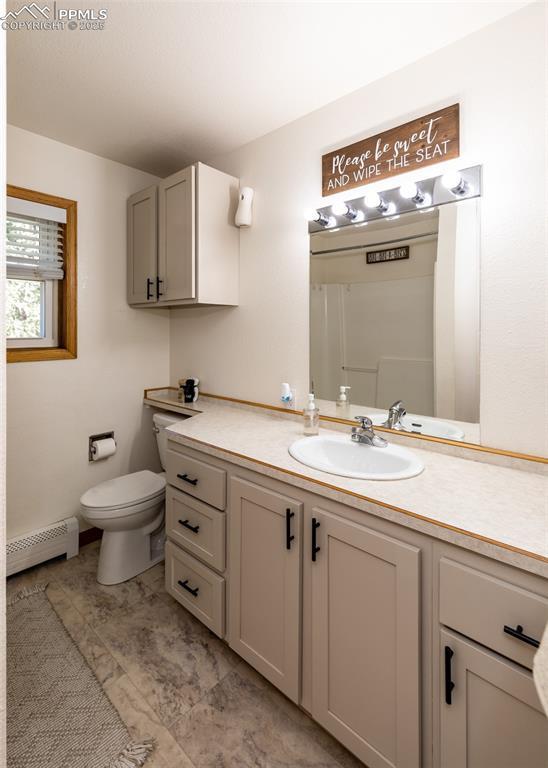 bathroom featuring toilet, vanity, and a baseboard heating unit