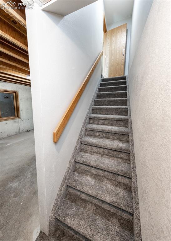 stairway featuring unfinished concrete flooring