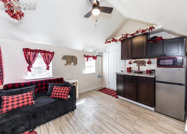 interior space with baseboards, lofted ceiling, light wood-style floors, and ceiling fan