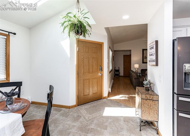 foyer featuring lofted ceiling, light tile patterned flooring, and baseboards