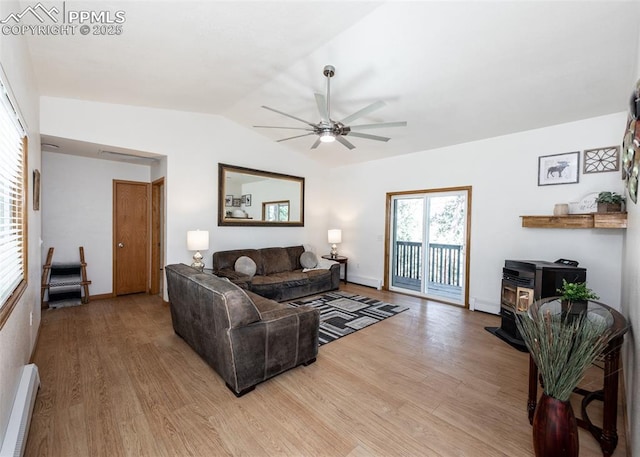 living area with lofted ceiling, a wood stove, light wood-style flooring, and baseboard heating