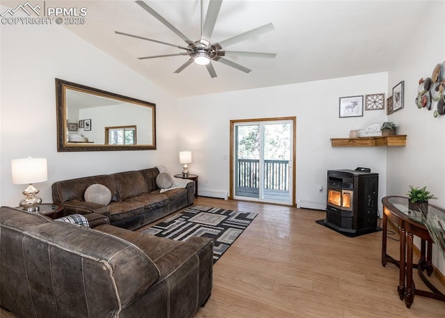 living area featuring ceiling fan, baseboards, lofted ceiling, a wood stove, and wood finished floors