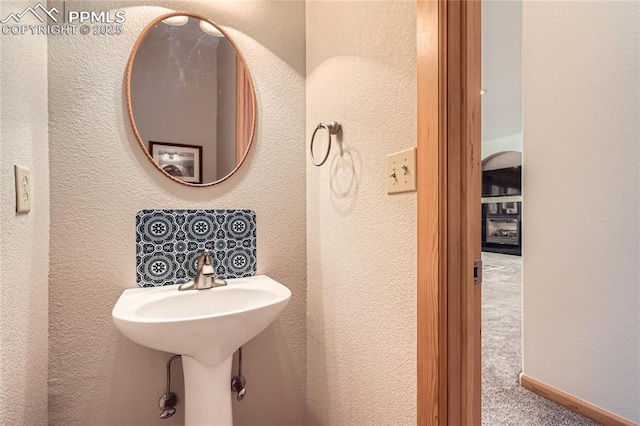 bathroom with a textured wall and baseboards