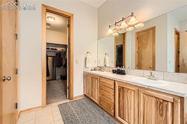 bathroom with a sink, a walk in closet, double vanity, and tile patterned flooring