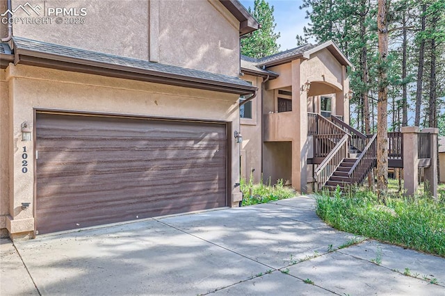 view of front of house with stairs, a garage, driveway, and stucco siding