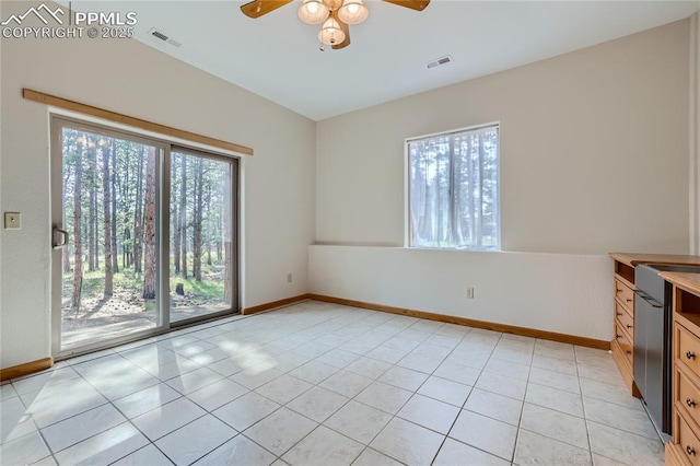 empty room with a wealth of natural light, light tile patterned floors, and baseboards