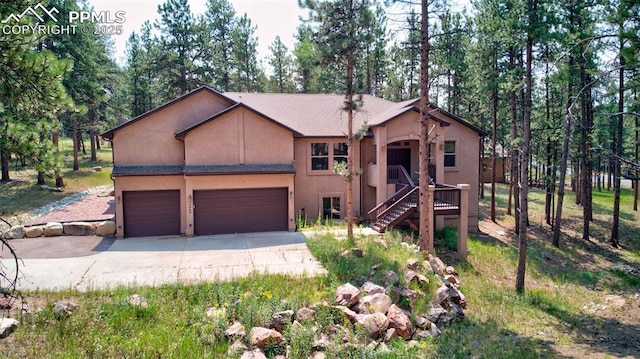 view of front of home with stairway, an attached garage, driveway, and stucco siding