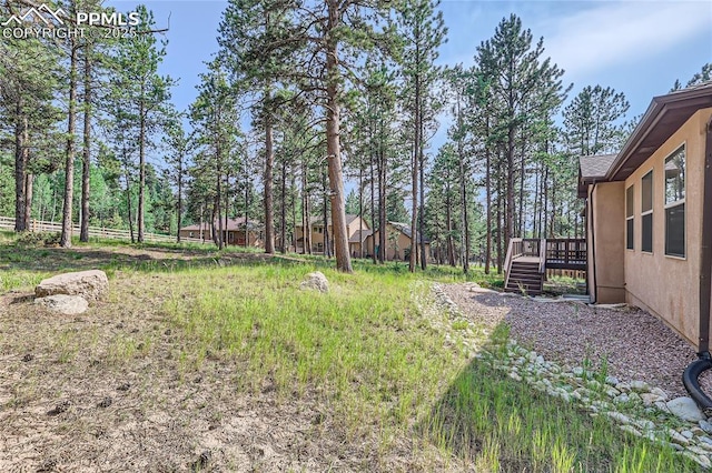 view of yard featuring a wooden deck, stairs, and fence