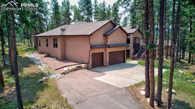 view of front of property featuring stairway, a garage, concrete driveway, and stucco siding