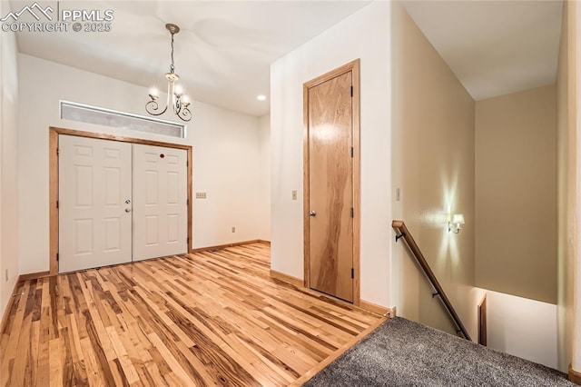 foyer featuring light wood finished floors, baseboards, and an inviting chandelier