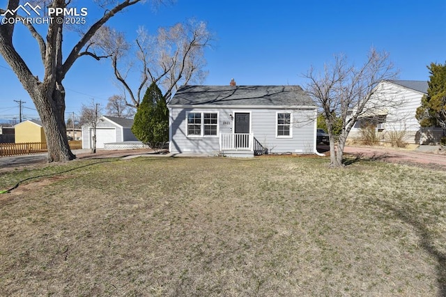 view of front of home with an outbuilding, a detached garage, a front lawn, and fence