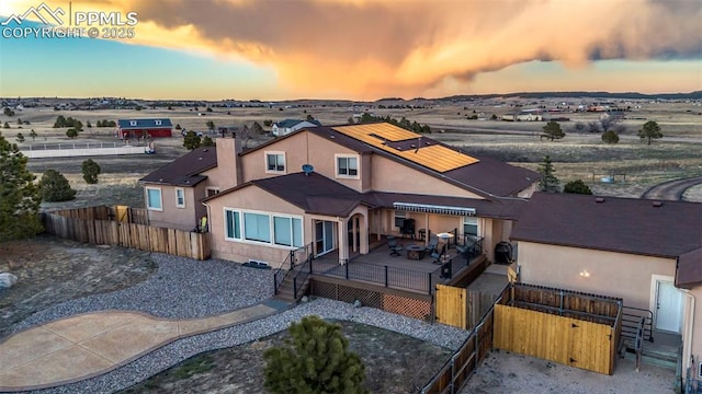 14650 Eastonville Rd, Elbert, CO 80106 - back of house at dusk with a deck, solar panels, and a fenced backyard