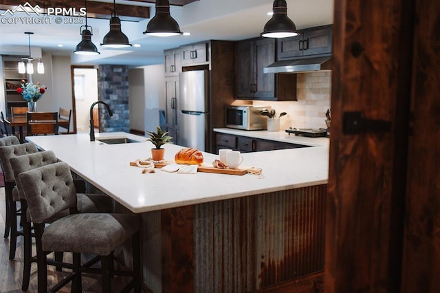 14650 Eastonville Rd, Elbert, CO 80106 - kitchen featuring light countertops, freestanding refrigerator, backsplash, white microwave, and under cabinet range hood