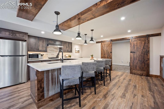 14650 Eastonville Rd, Elbert, CO 80106 - kitchen featuring freestanding refrigerator, dark brown cabinets, white microwave, a barn door, and light countertops