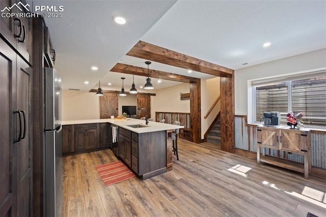 14650 Eastonville Rd, Elbert, CO 80106 - kitchen featuring dark brown cabinetry, appliances with stainless steel finishes, a sink, a wainscoted wall, and wood finished floors