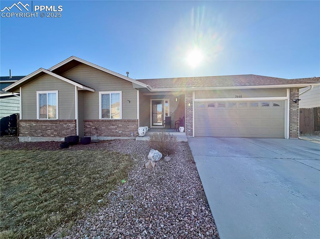 ranch-style home with a garage, a front lawn, brick siding, and driveway