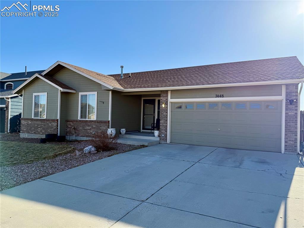 ranch-style house with brick siding, concrete driveway, a garage, and a shingled roof