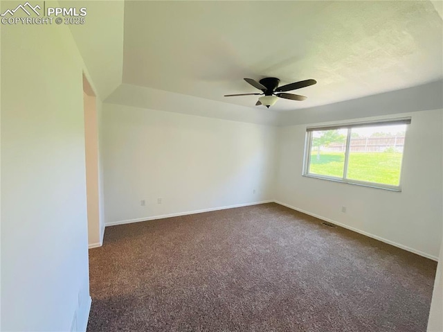 spare room with dark carpet, a ceiling fan, and baseboards