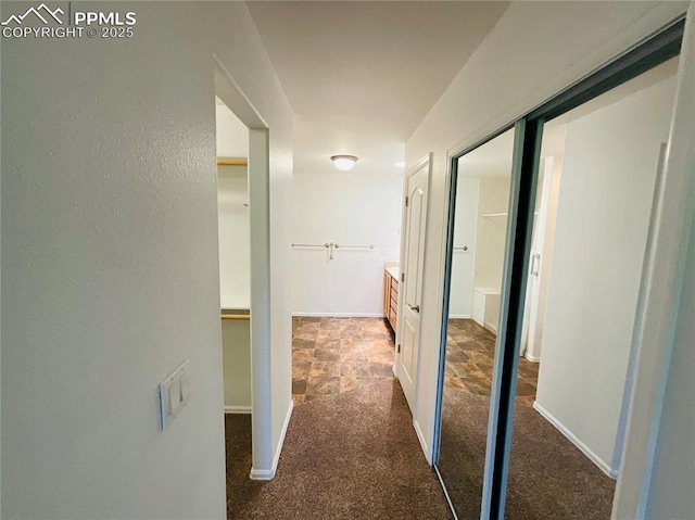 hall featuring stone finish flooring, baseboards, and carpet flooring