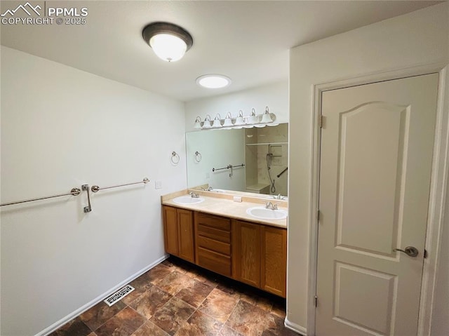 bathroom with double vanity, a walk in shower, visible vents, and a sink