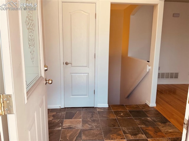 hall with visible vents, stone finish flooring, and baseboards