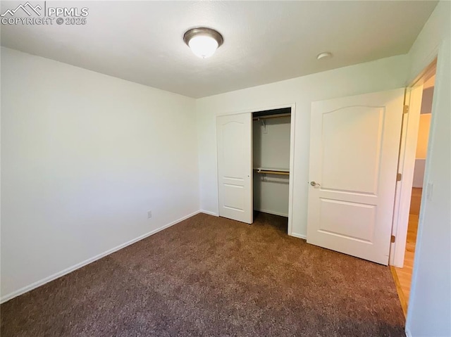 unfurnished bedroom featuring a closet, dark carpet, and baseboards