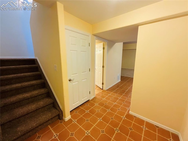 stairway with tile patterned floors and baseboards