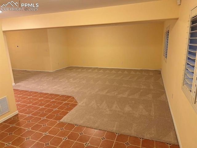 spare room featuring baseboards, visible vents, and carpet floors