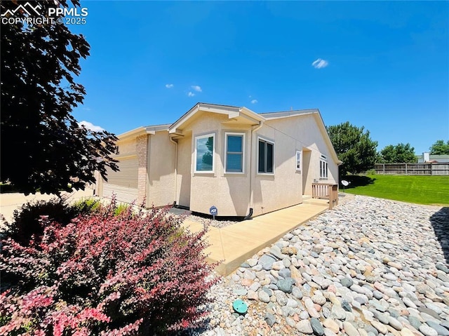 view of side of home with a yard, fence, a garage, and stucco siding