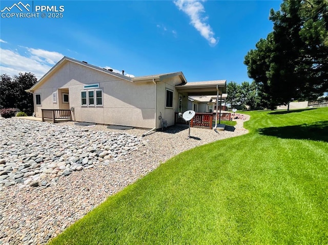 rear view of house featuring stucco siding, a patio, and a lawn